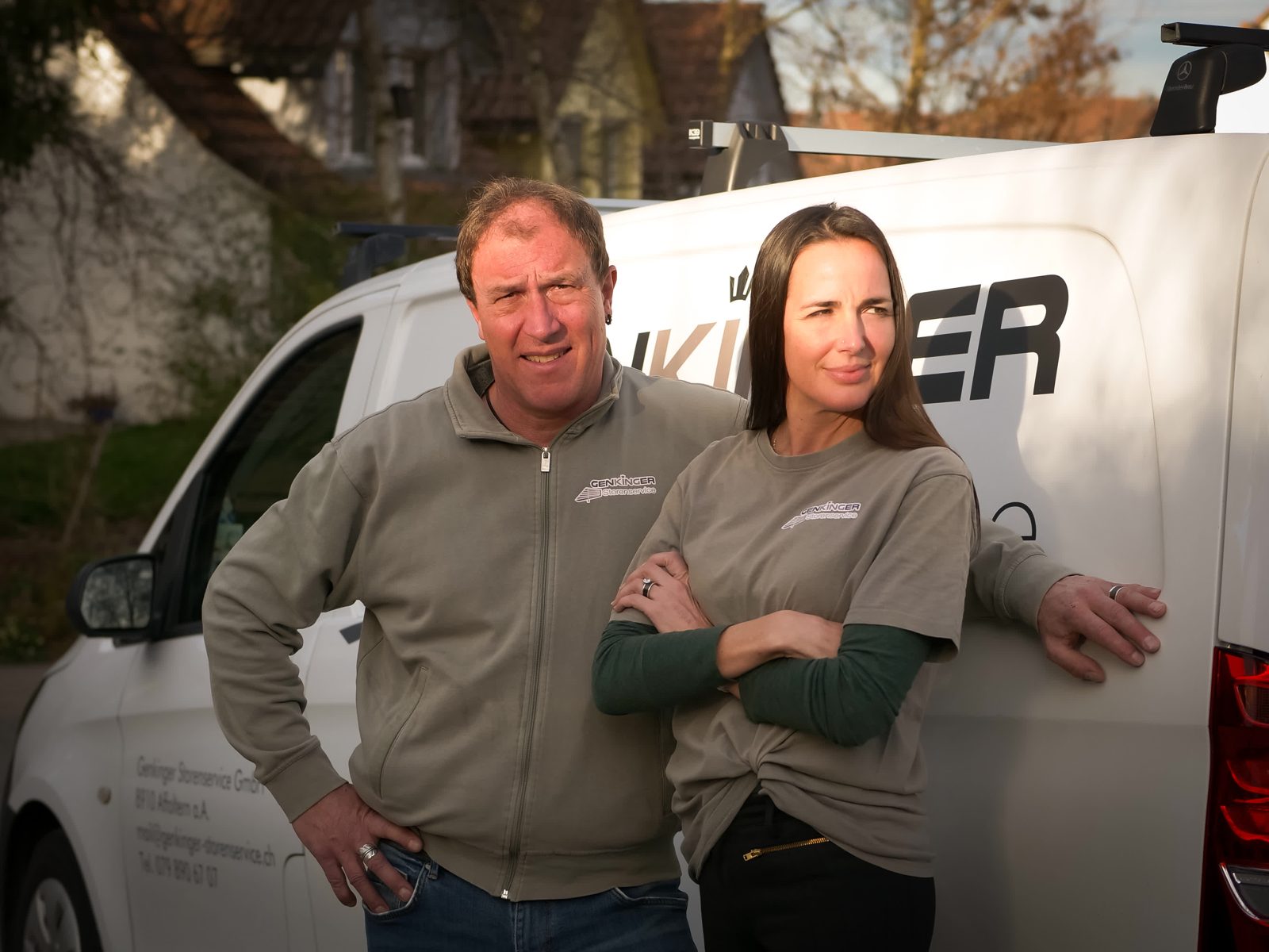 Raffaela und Mario Genkinger mit verschränkten Armen vor dem Firmenbus